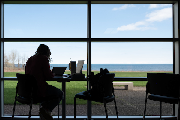 Studying student silhouetted by window with a view of Lake Michigan