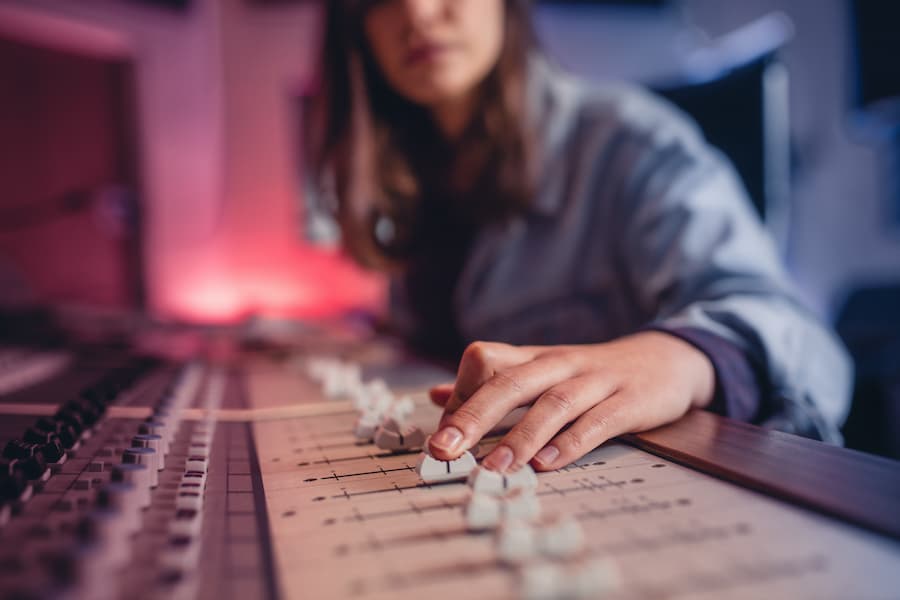 Musician adjusts audio mixer slider on an electronic sound board