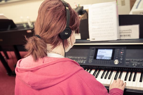 Student wears headphones while playing the keyboard