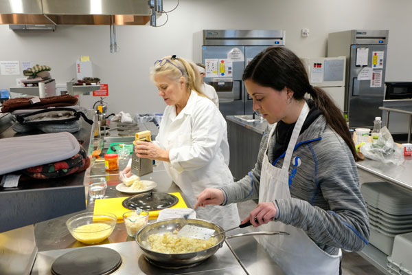 Teach and student prepare food in industrial kitchen
