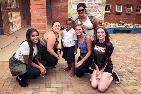 Students pose with child in Africa