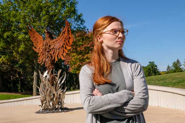 Student poses in front of Phoenix Sculpture