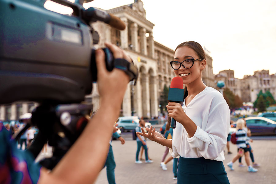 Female Foreign Correspondent holds microphone while reporting news overseas