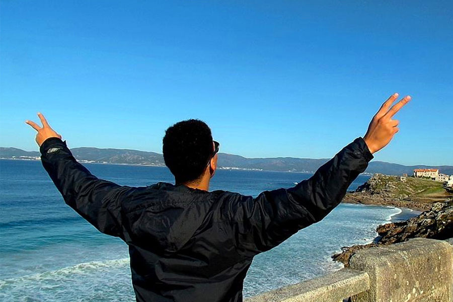 Spanish student giving the peace sign while overlooking the ocean
