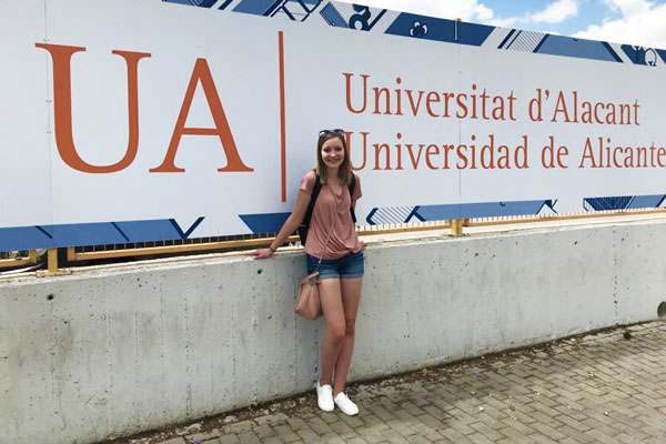 Female student stands in front of Universitat d'Alacant sign