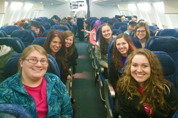 Spanish students smile for photo on their flight abroad