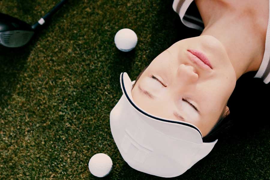 Female golfer lays by golf balls and club