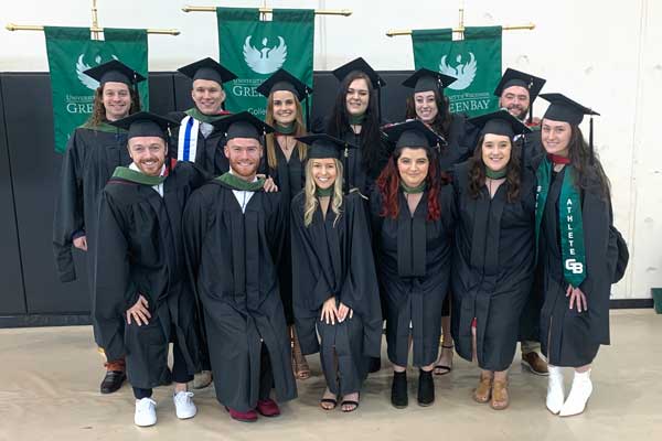 Sports Performance and Psychology graduates pose for photo in cap and gown