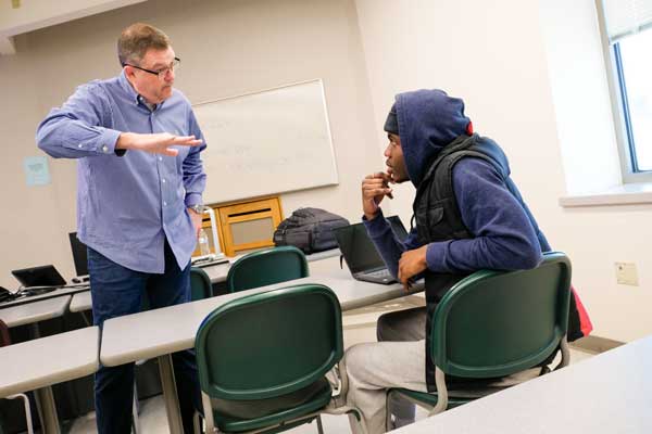 Professor works with african american male student in class