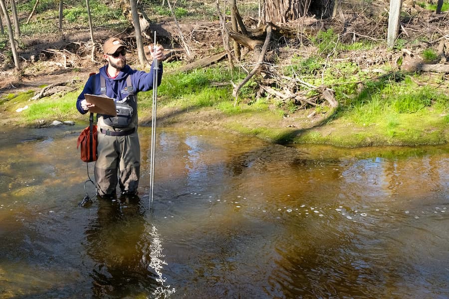 An Environmental Science and Policy graduate student tests the stream depth in Mahon Creek during Aquatic Invertebrates fieldwork lab. Mahon Creek runs through the Cofrin Arboretum at UW-Green Bay campus.