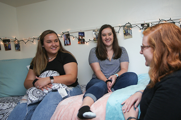Students sitting in a UW-Green Bay dorm room that's decorated with miniature holiday lights