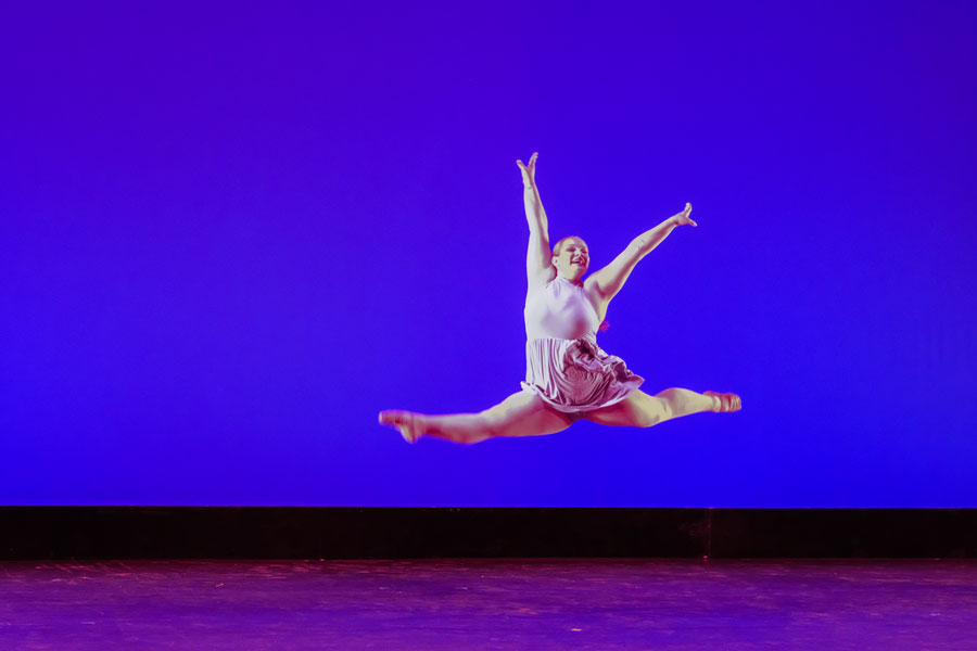 Dance student performs split leap on stage