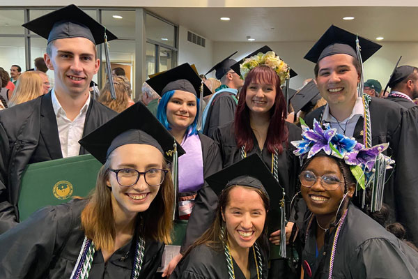 Theatre and Dance students pose for photo in graduation cap and gown