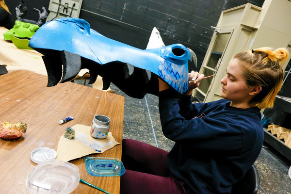 Student paint dragon head in props and design class