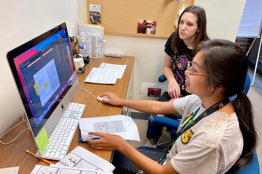Two female students work on writing project using Adobe Indesign
