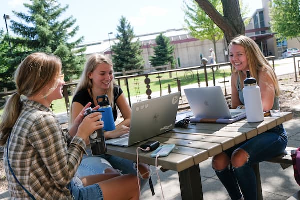 Three female students work outdoors on the UWGB campus