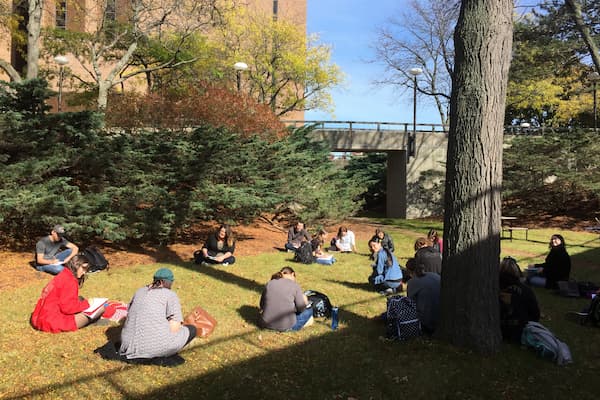 Students outside writing on one of our beautiful campuses