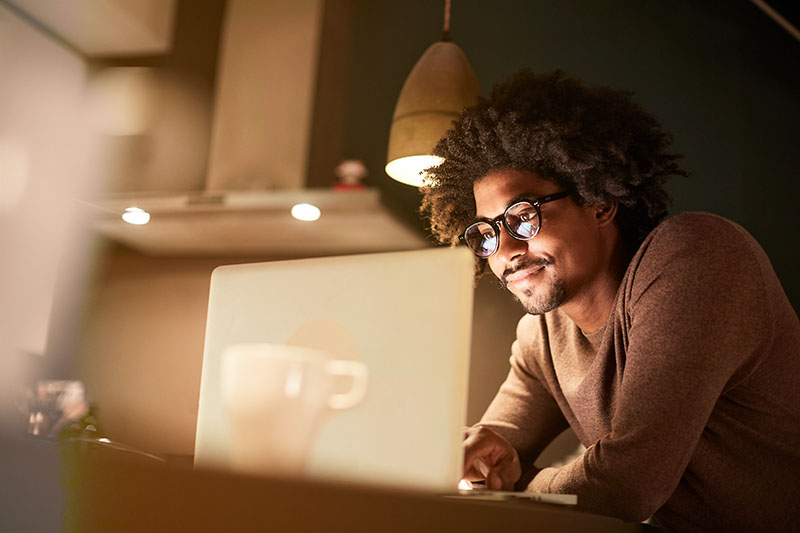 Man working on laptop at a dining room table
