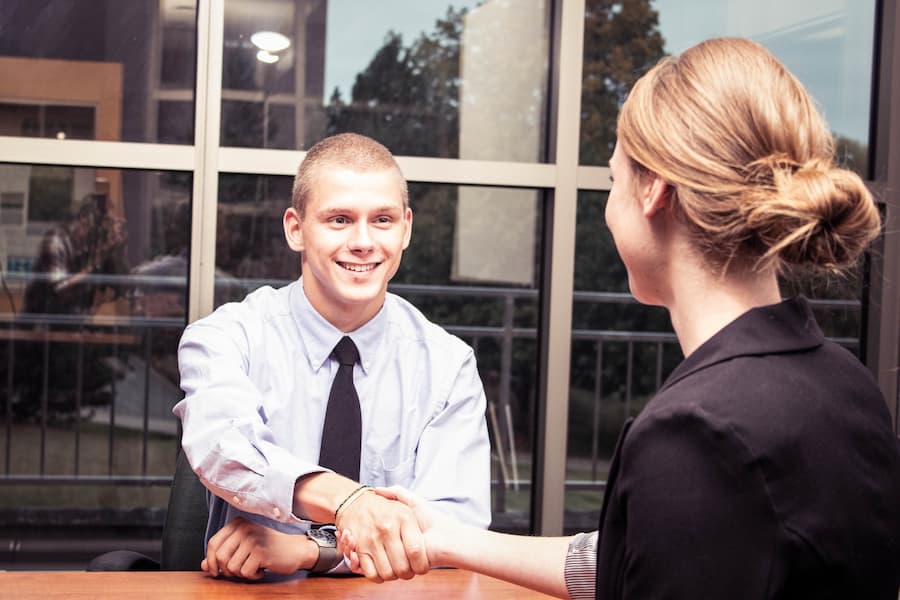 Male student shakes hands with female accountant during internship interview
