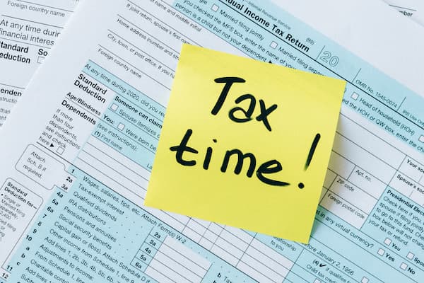 Tax forms with a post it note reading "Tax Time!"