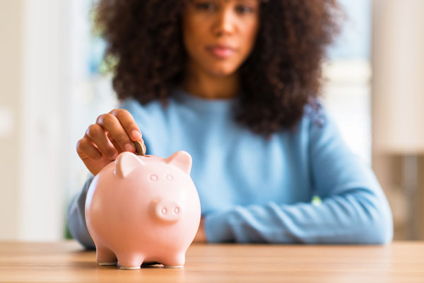 African American female putting change in piggy bank