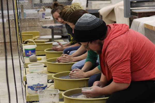 Group of students work on potter's wheel