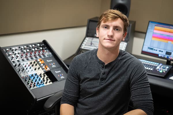 Audio production student sitting at sound board
