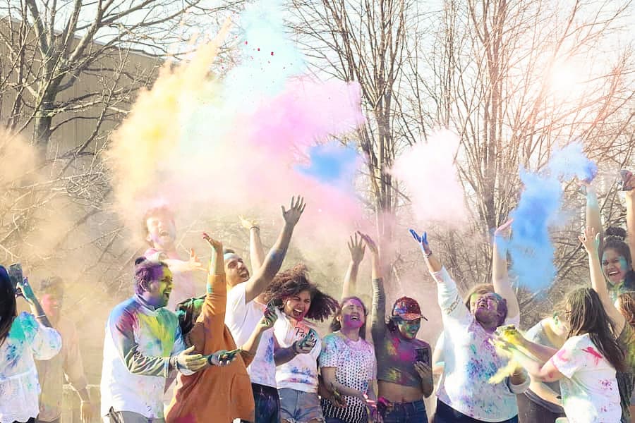 Students throw colorful powder into the air for Hala Festival.