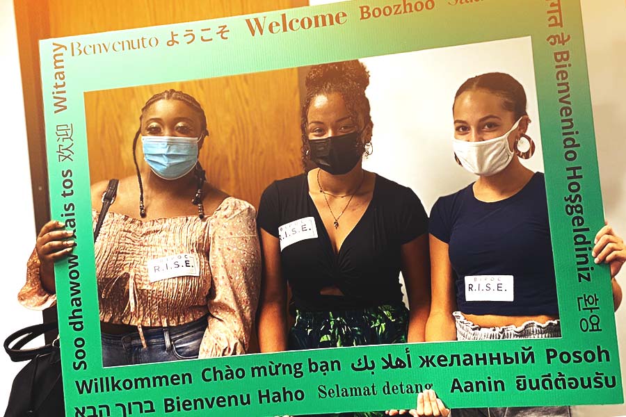 Three BIPOC mentors hold welcome sign.