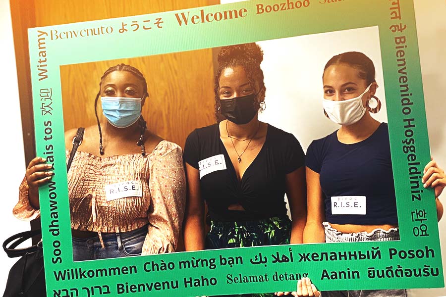 Three BIPOC mentors hold welcome sign.