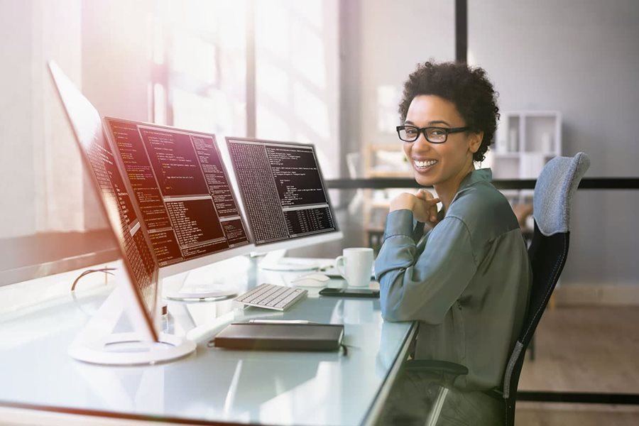 Middle aged woman in front of three monitors