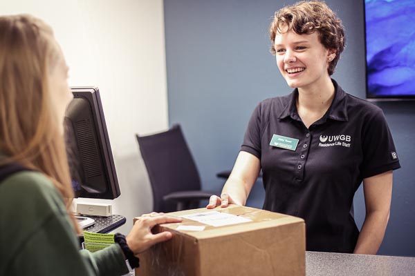 ResLife Mailroom worker helping a resident with a package