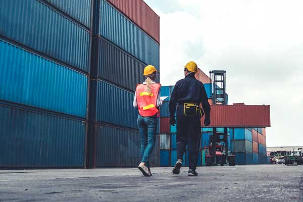 Two collegues walk through yard of shipping containers