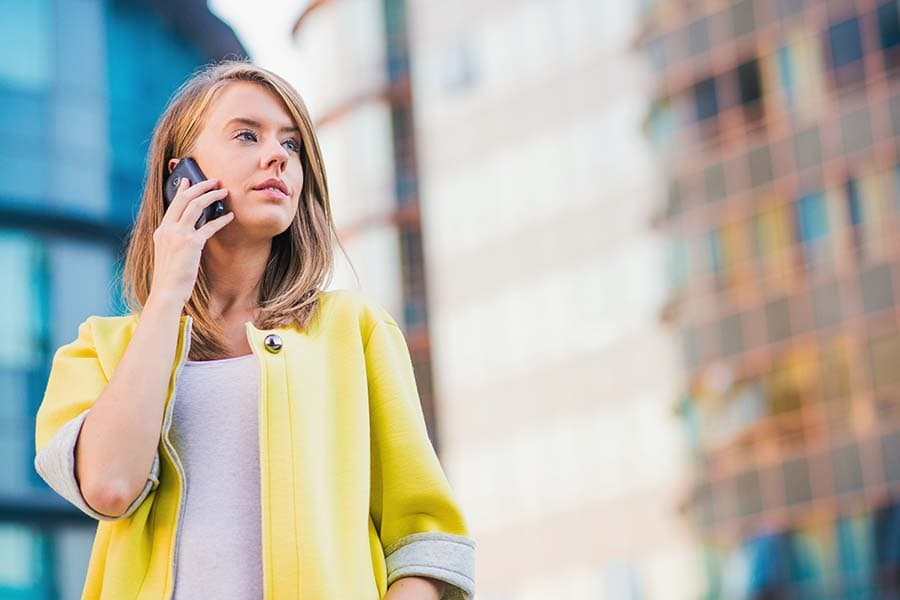 business woman looking up standing outside talking on smartphone