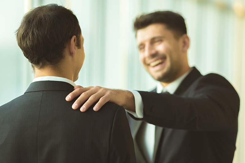 Businessman patting man on shoulder