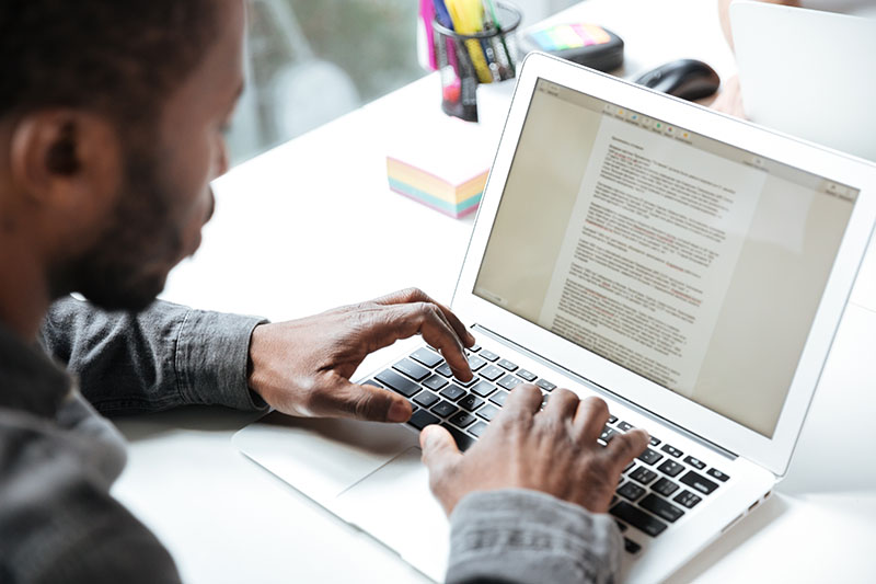 Man typing resume on laptop