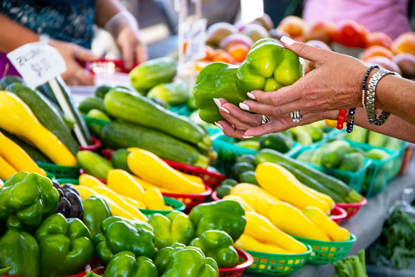 Close up of woman picking out green peppers at farmer's market