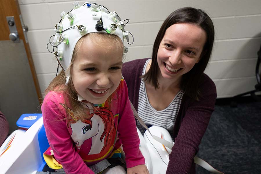 UW-Green Bay psychology research assistant working with child wearing a neuroscience cap