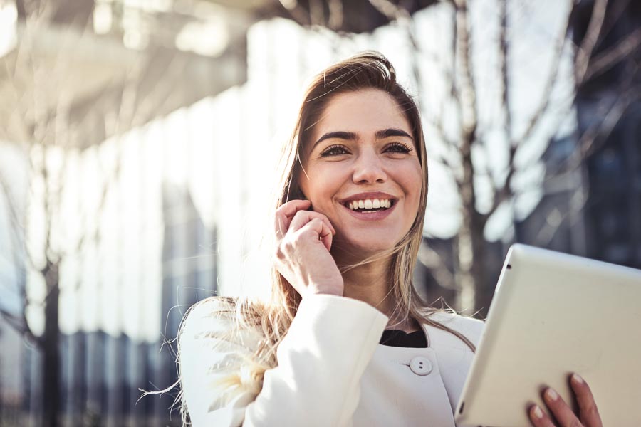 Young woman taking on the phone with a tablet in her other hand