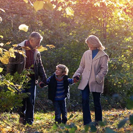 two grandparents walking outside with their young grandchild