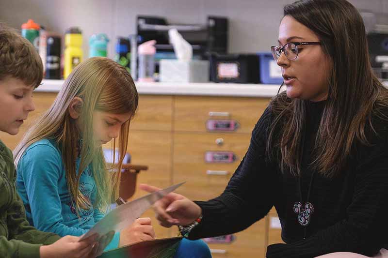 Majriela Macedo student teaching with two elementary school students