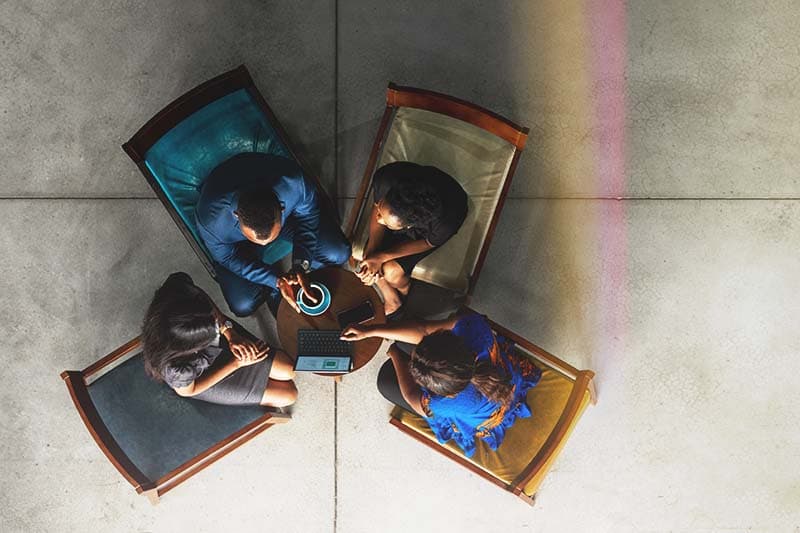 overhead view of group of four people sitting in chairs during meeting