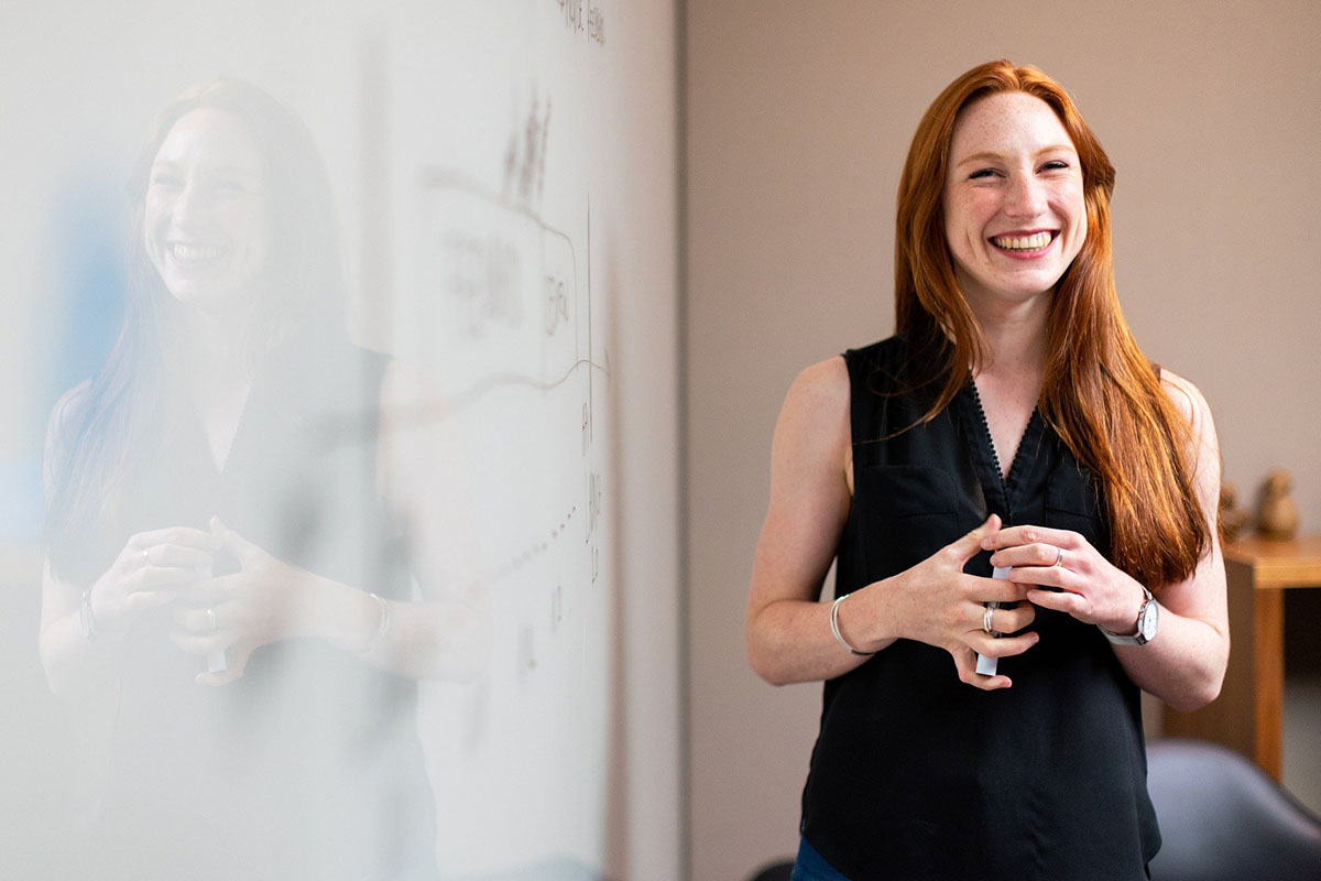 Smiling woman standing by dry erase board