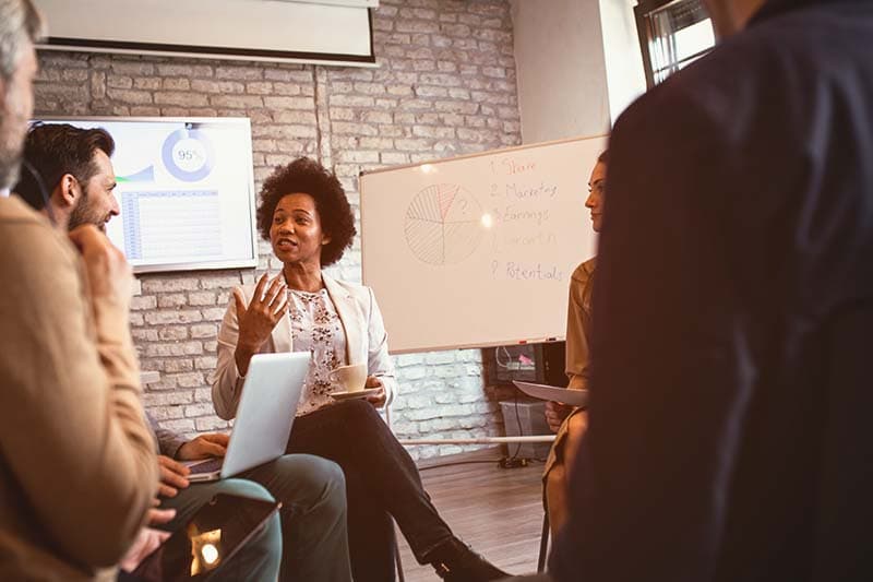 woman talking during a meeting with marker board in background