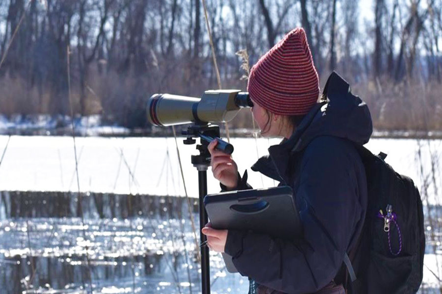 UW-Green Bay student outdoors looking through binoculars
