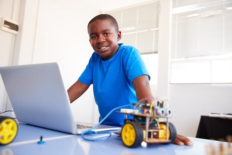 Young man at a laptop programming small robotics