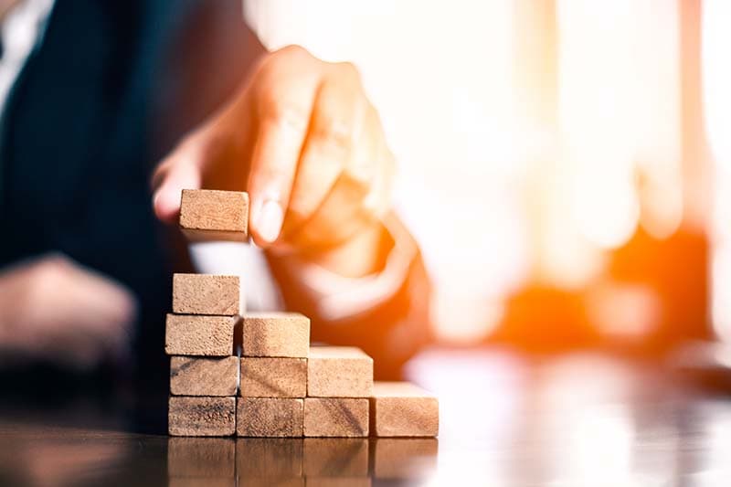 closeup of hand placing wooden block to form steps