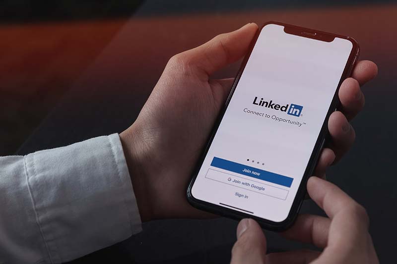 man holds smartphone with LinkedIn app