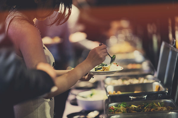 woman in buffet line scooping food onto a plate
