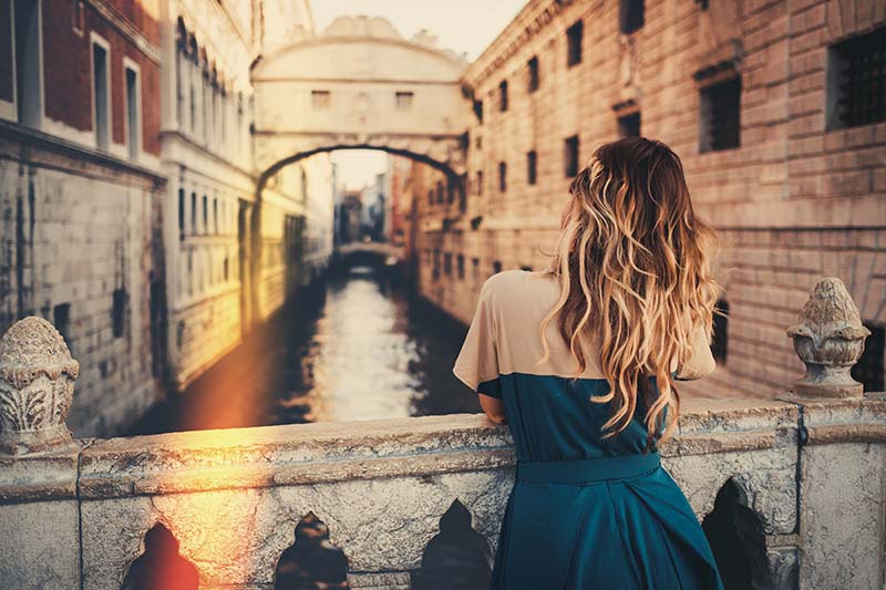 woman standing on bridge over canal in Italy